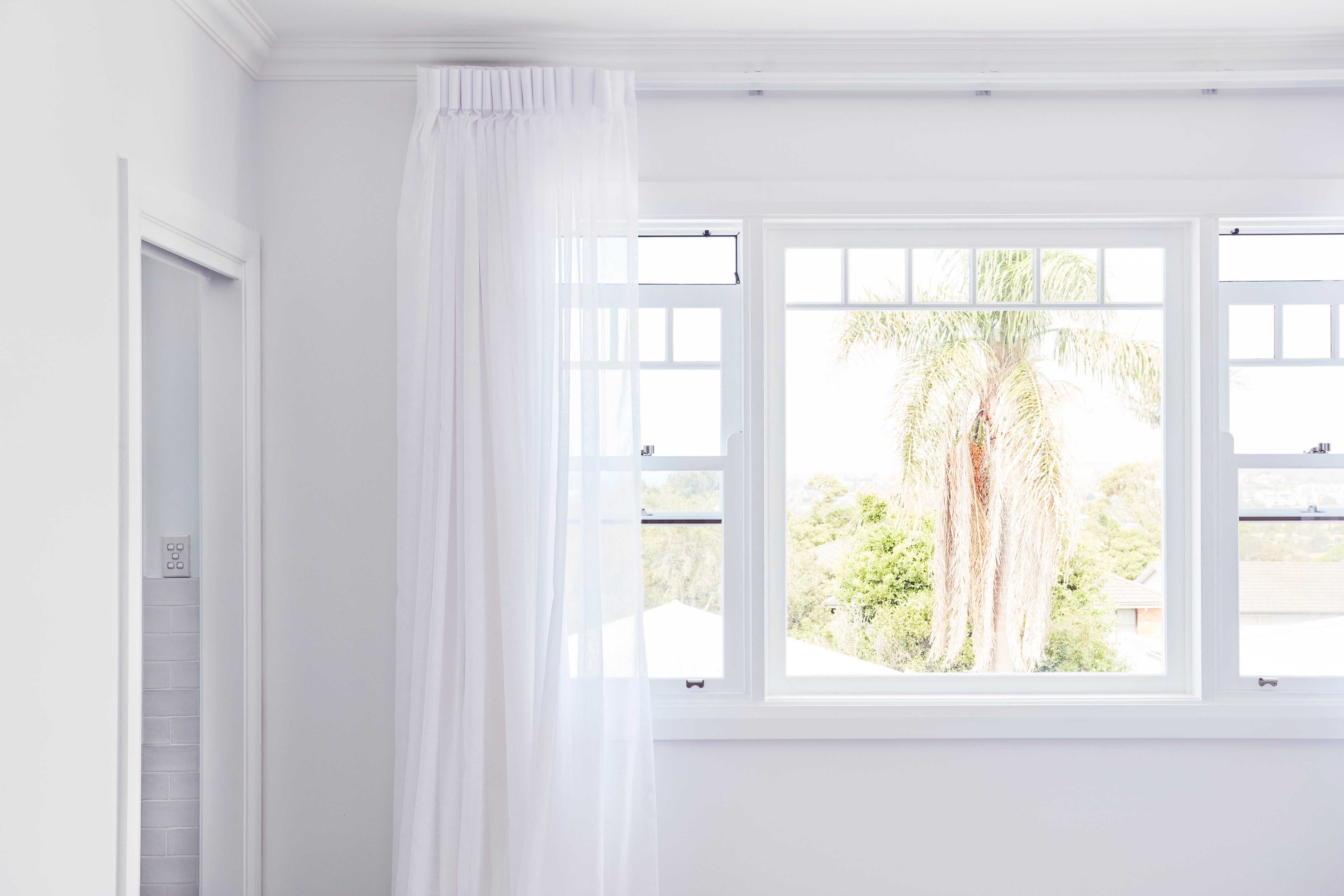 White double hung window frame with curtains in a bright room