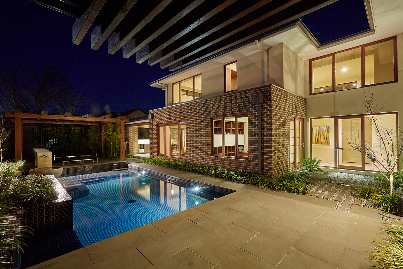 Modern house with timber windows and door and a pool at night