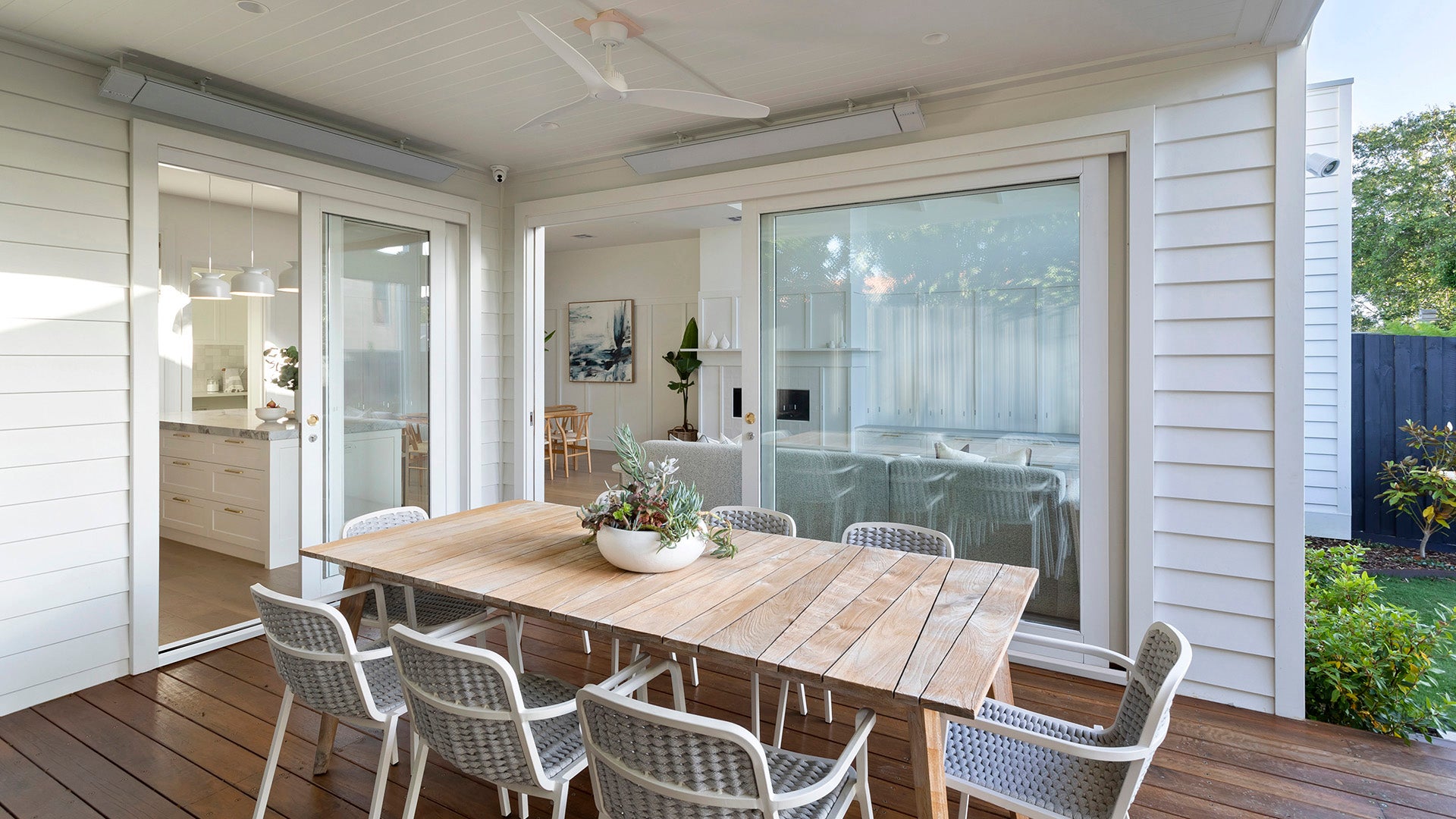 Outdoor dining area with wooden table and large timber sliding and stacking glass door.