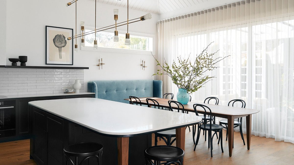 Modern kitchen with a large island, dining table, and chairs.
