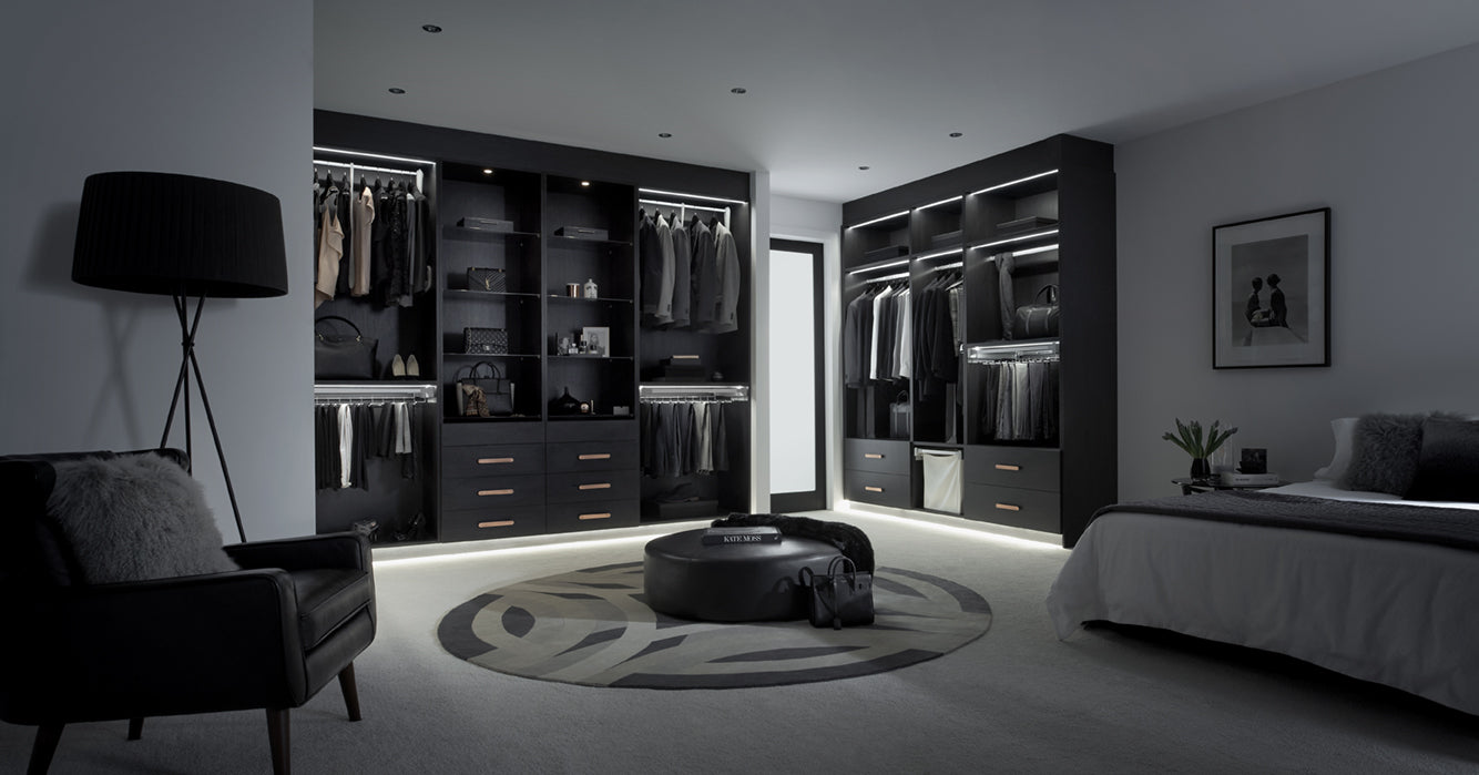 Modern bedroom with walk-in wardrobe and bed in a dark setting