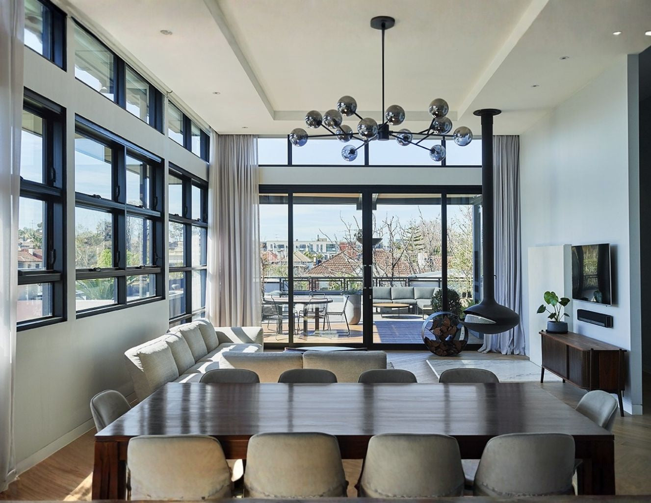 Modern living room with large windows, a dining table, and chairs.
