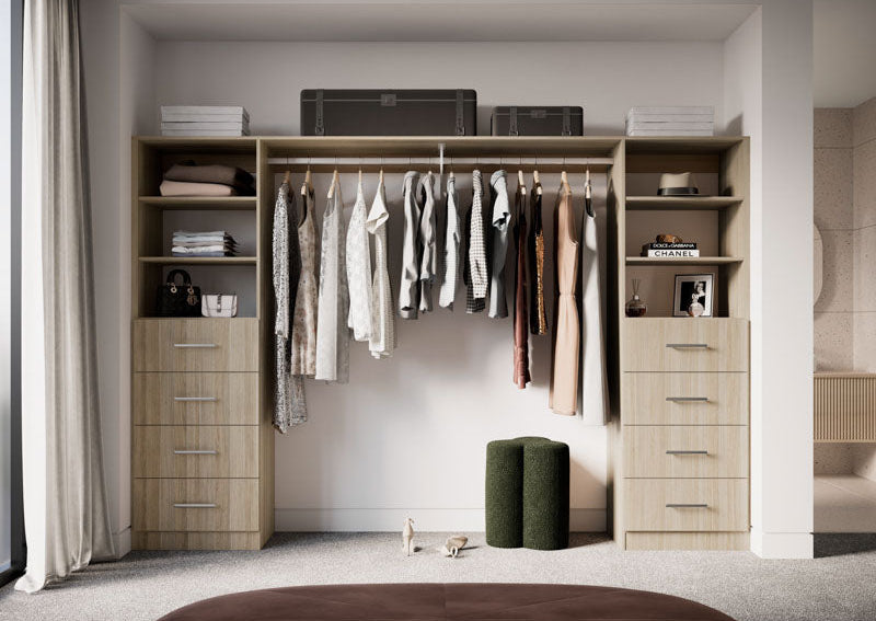 Modern walk-in closet with wooden shelves and clothes, featuring a brown ottoman in the foreground.