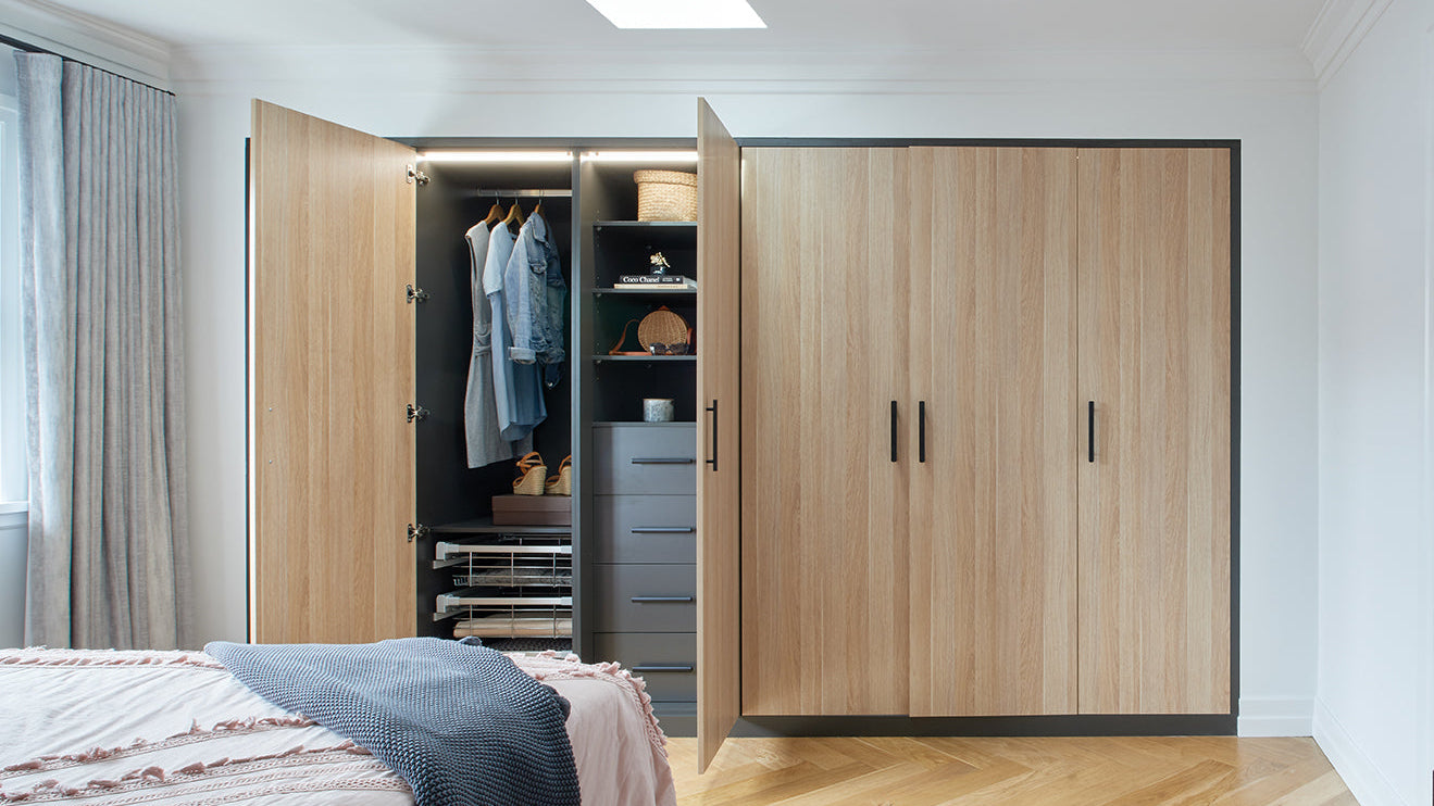 Wooden wardrobe with open doors in a bedroom setting