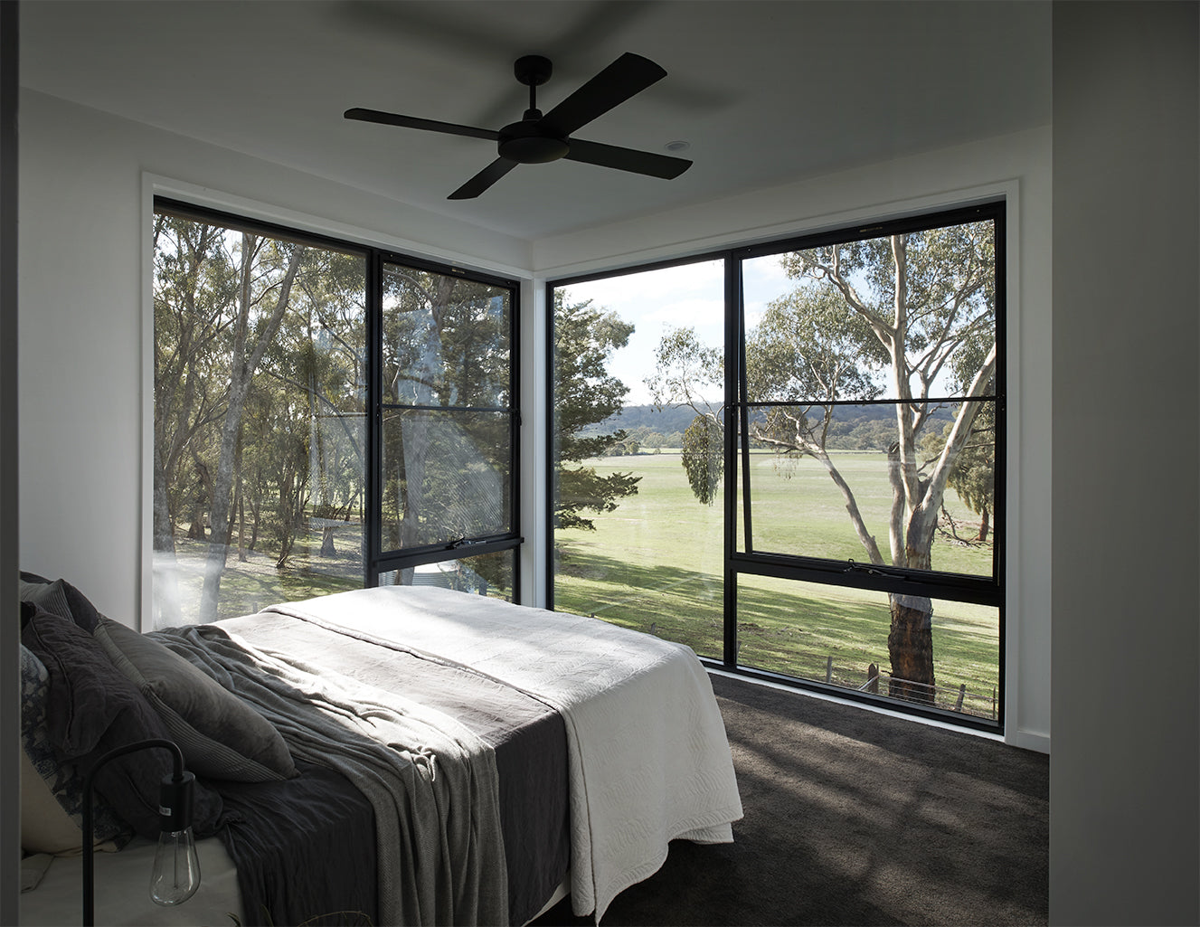Modern bedroom with large windows offering a view of trees and greenery