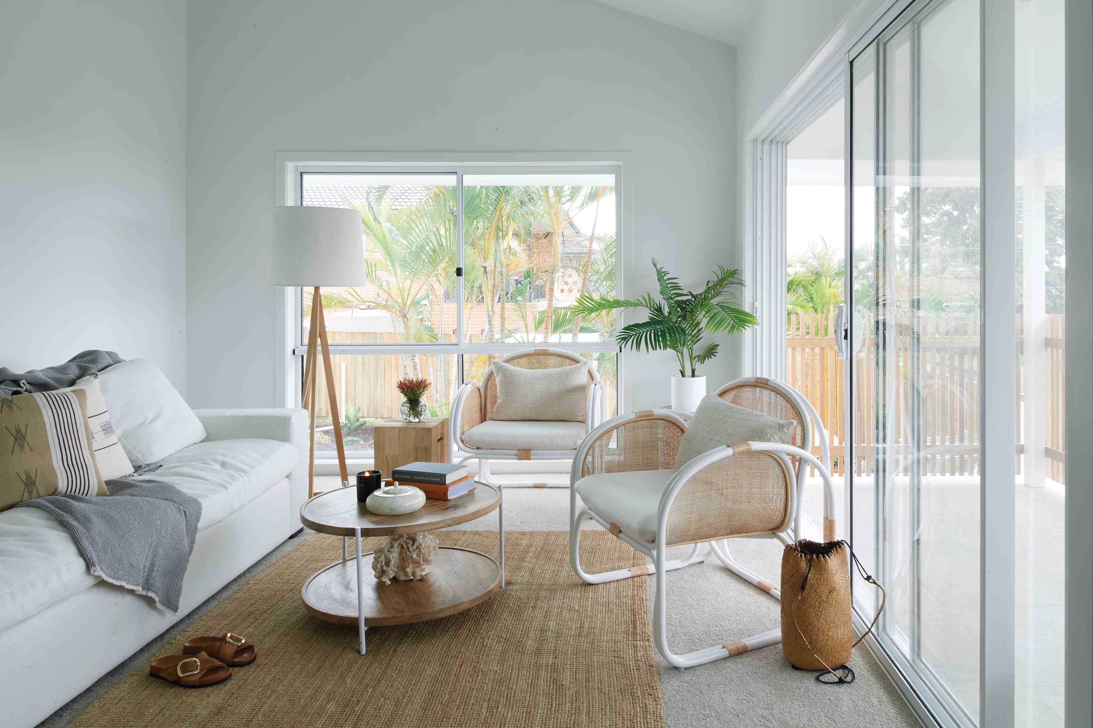 Modern living room with white sofa, wicker chairs, and a sliding glass door.