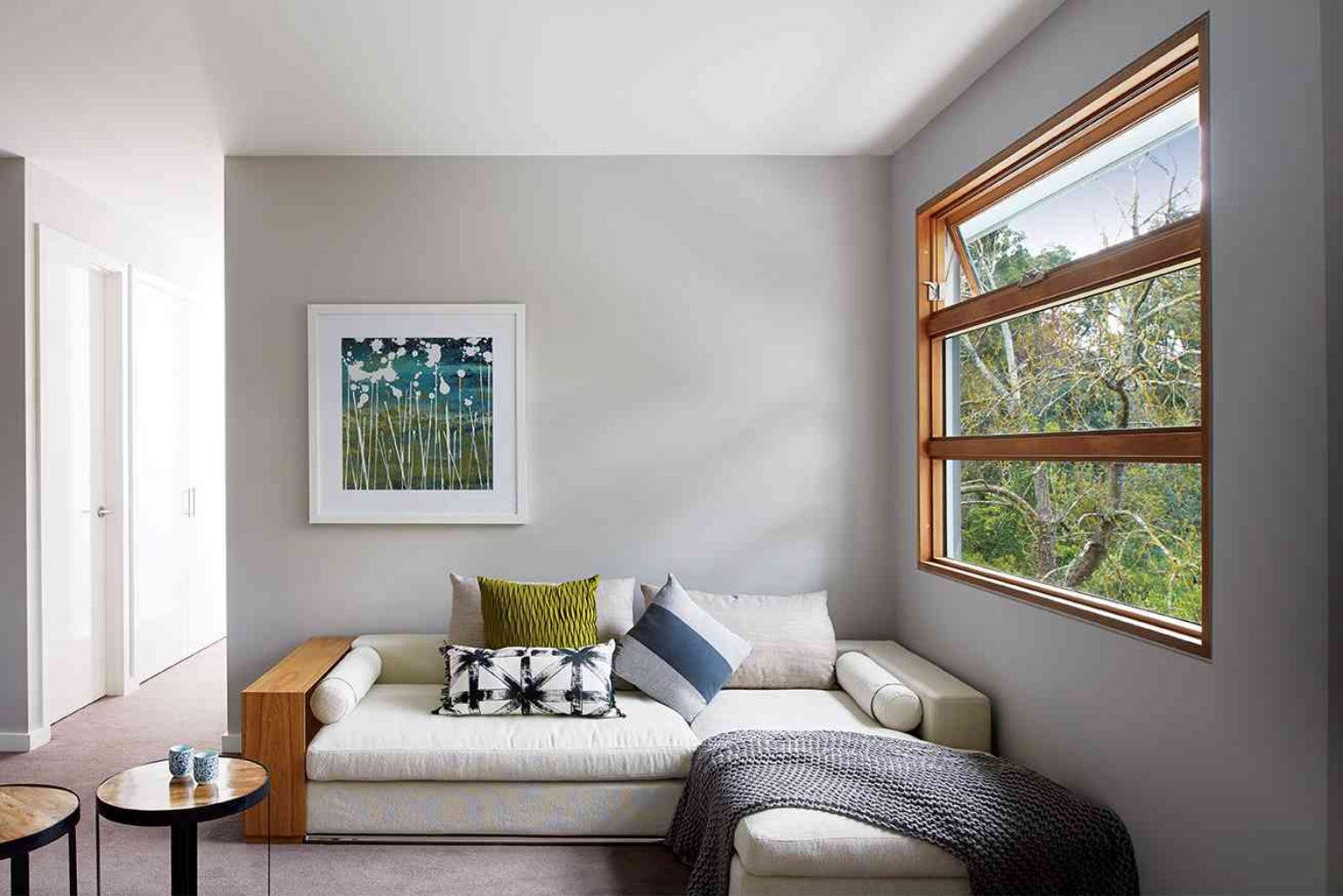 Modern living room with a sectional sofa, decorative pillows, and timber window.