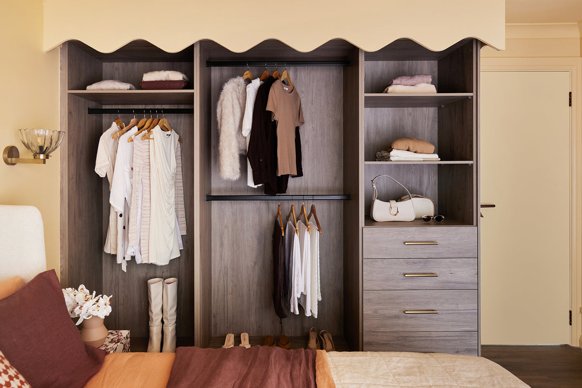 Closet with clothes hanging on racks and shelves in a bedroom setting.