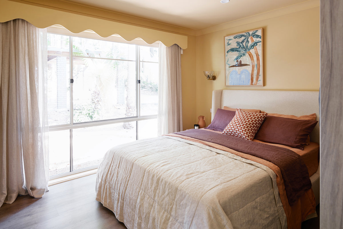Bedroom with a large window, bed with pillows, and wall art.