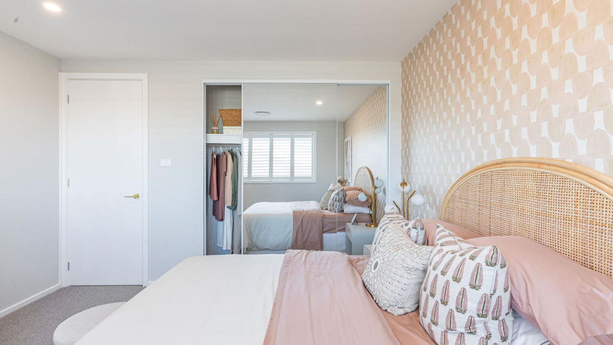 Neatly arranged bedroom with a bed, frameless sliding wardrobe, and decorative elements.