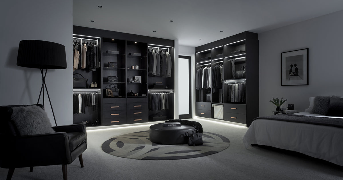 Modern bedroom with walk-in wardrobe and bed in a dark setting
