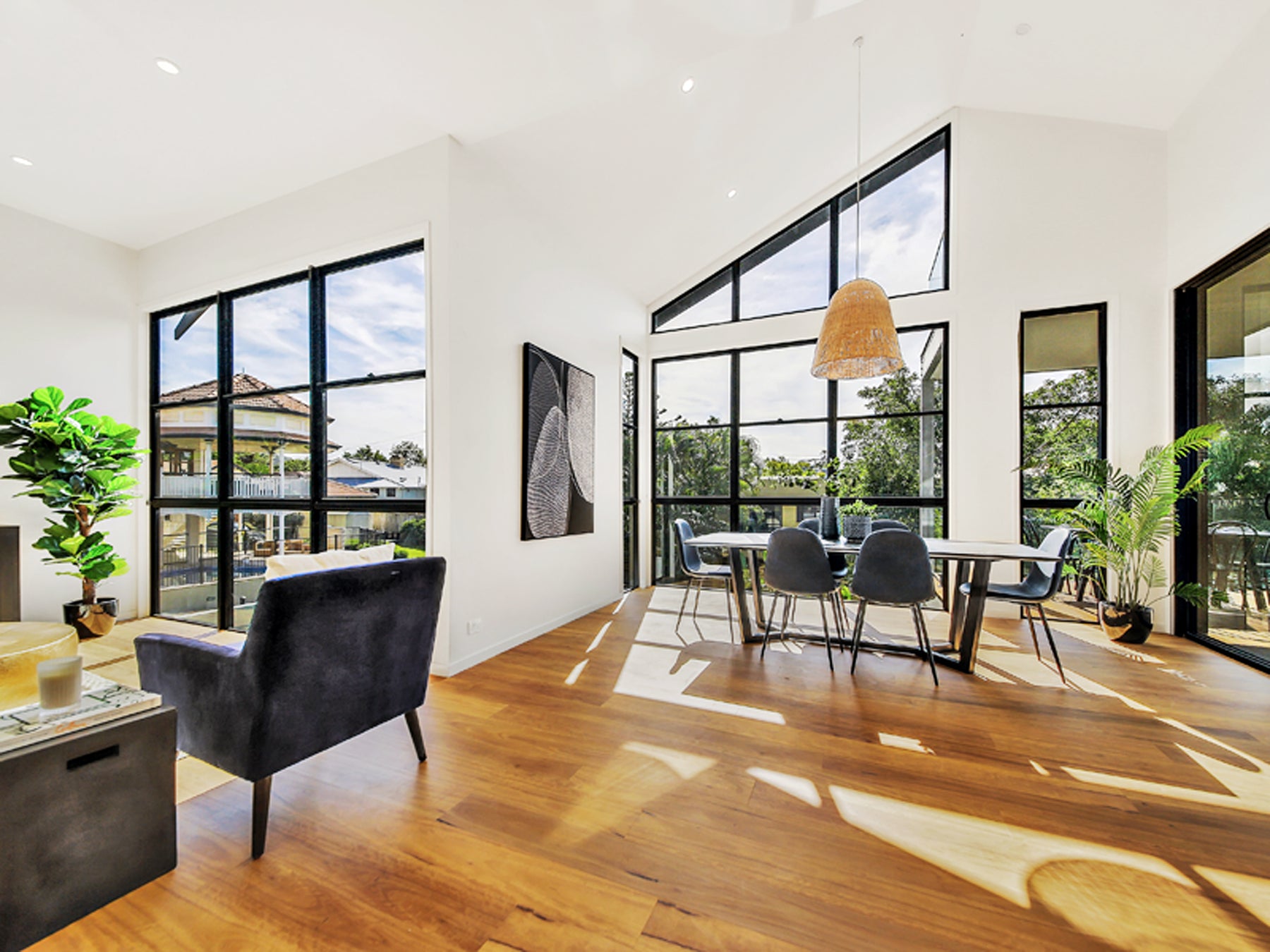 Modern living room with large windows, wooden floor, and furniture.