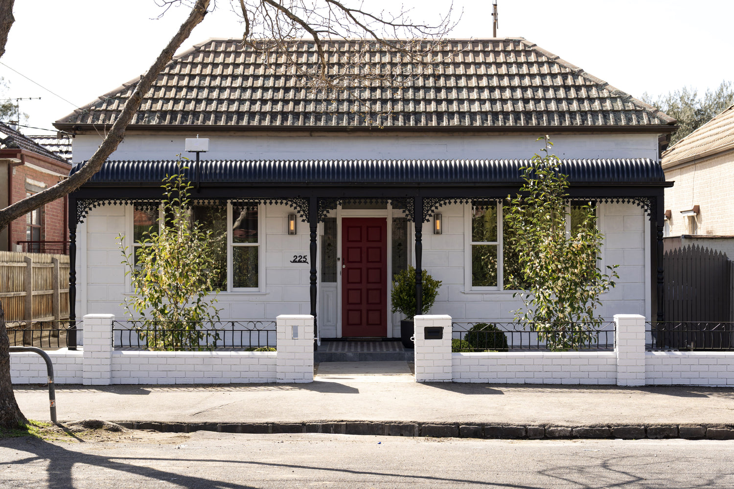 White house with a red door and black roof in a residential area