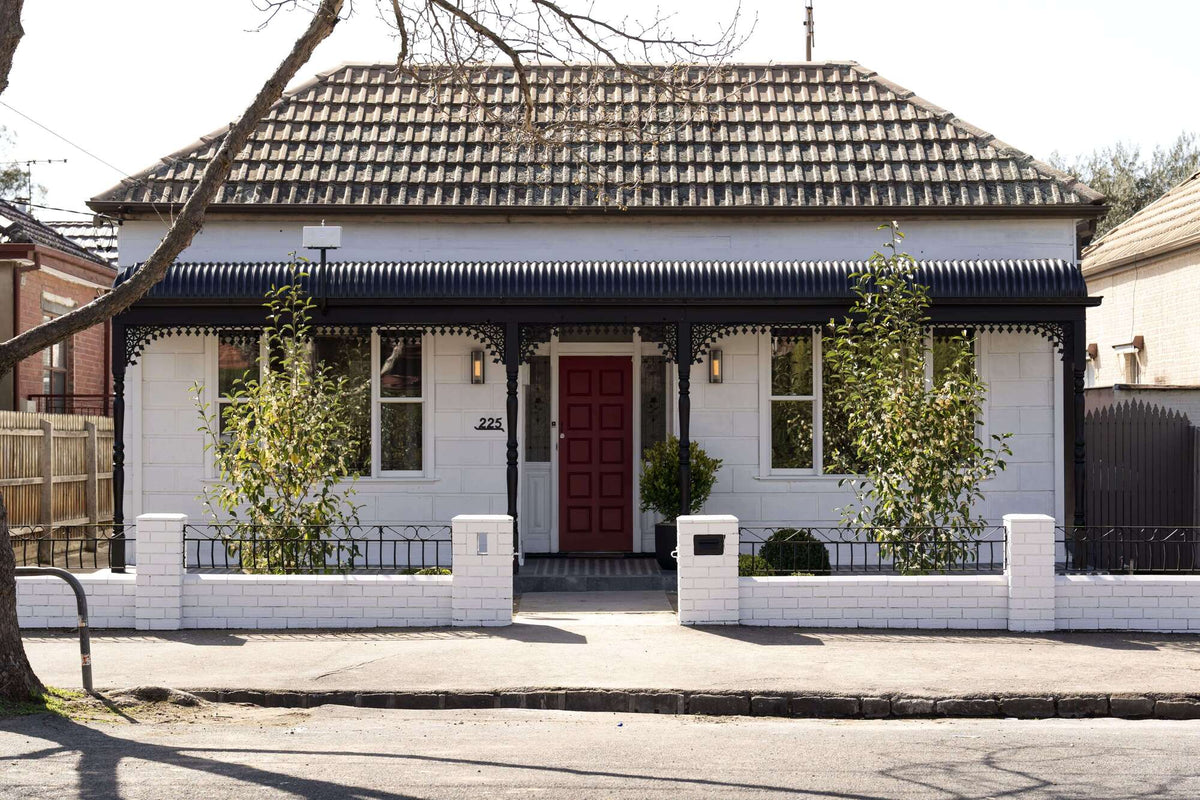 White house with a red door and black roof in a suburban setting