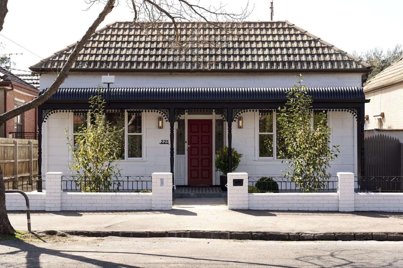 White house with a red door and black roof in a suburban setting
