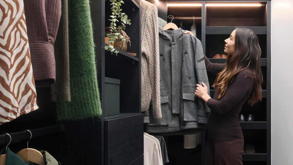 Woman in a modern wardrobe with clothes hanging on racks