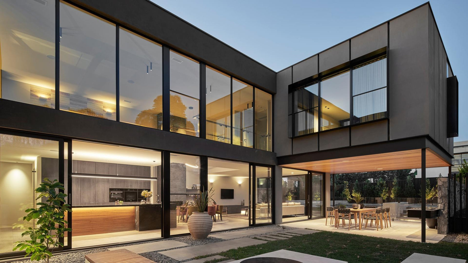 Modern house with large glass windows and a well-lit interior.