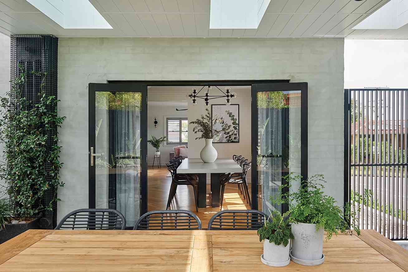 Modern interior with a dining table and chairs, large mirror, and decorative elements.